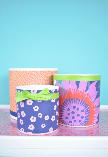Cylinder vases decorated with with brightly colored wrapping paper and green ribbon.  