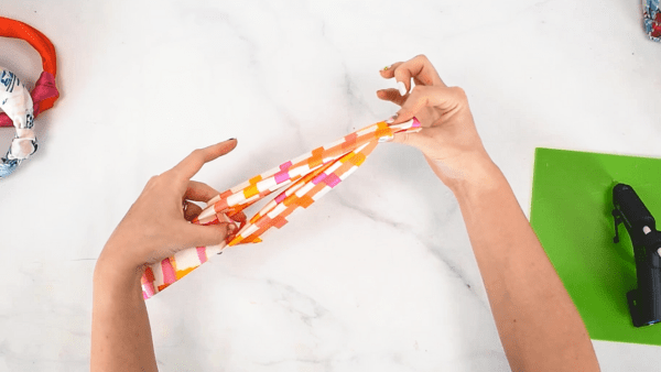 An overhead view of step four in the no-sew fabric top knot headband tutorial. In this step, you want to make sure the ends of your knot are evenly spaced and reach each end of the underlying headband form. 