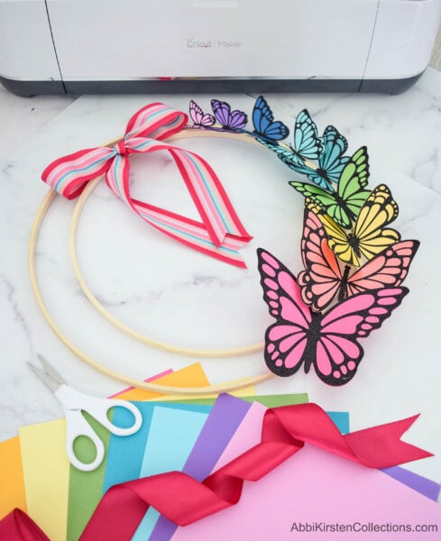 A colorful paper butterfly wreath made with rainbow paper butterflies and embroidery hoops.
