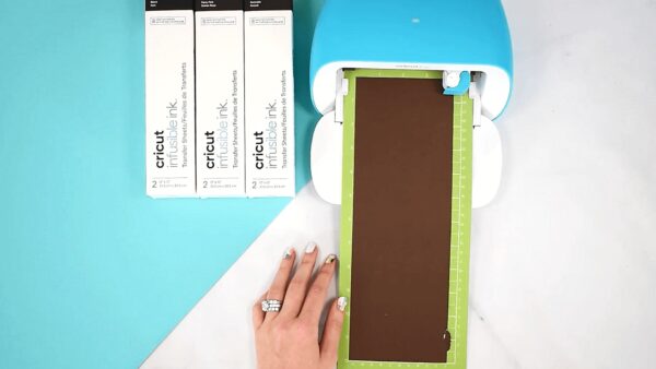 Abbi Kirsten's hand helps load a Cricut Joy machine with infusible ink. 