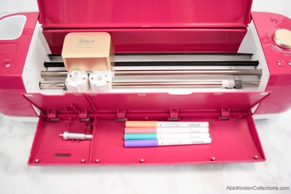 A red, open Cricut Explorer machine as seen from above. This beginner's guide to Cricut cutting machines will help you feel confident about crafting. 