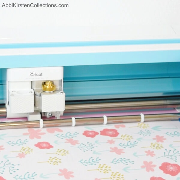 A close-up of a Cricut cutting machine cutting floral fabrics. Yes, you can use fabrics with your Cricut!