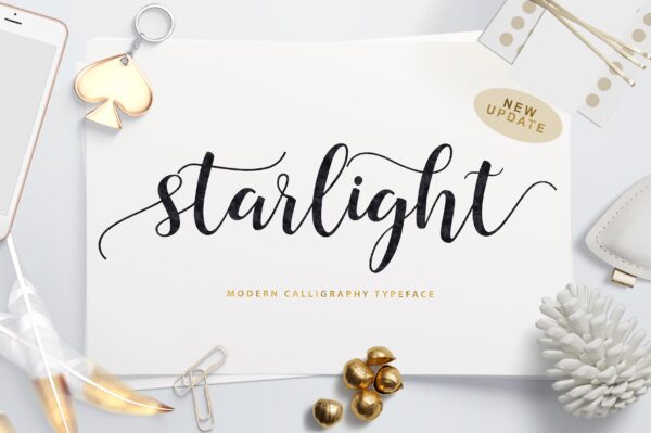 "Starlight" in black text is written across a white paper, surrounded by white and golden objects like a pinecone, paperclips and feathers. 