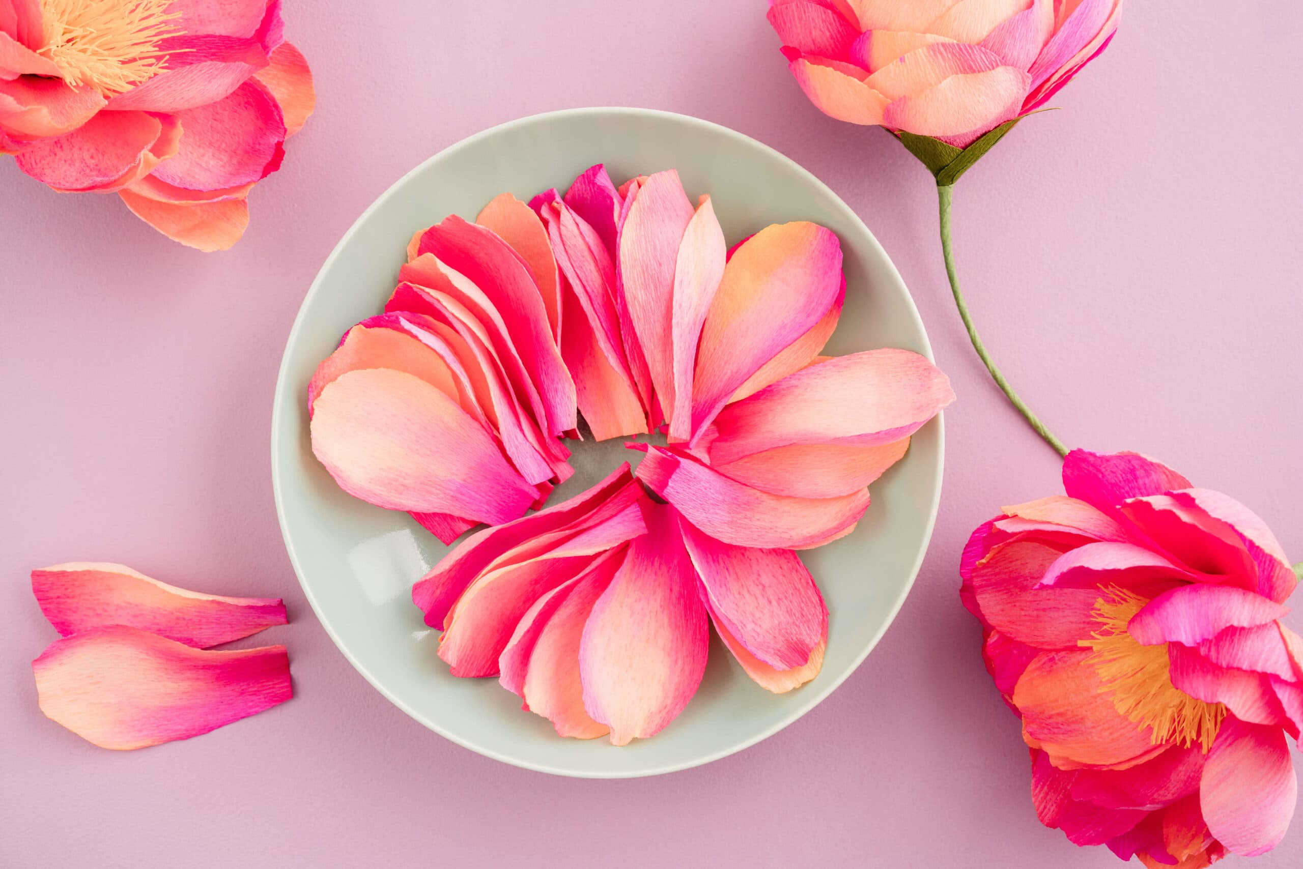 A bowl full of crepe paper flower petals, colored peach and pink with distress ink.