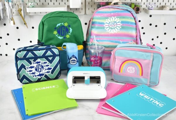 A collection of kids school supplies - backpacks, lunch boxes, notebooks, and cups - customized with vinyl decals made with the Cricut Joy cutting machine and smart vinyl.