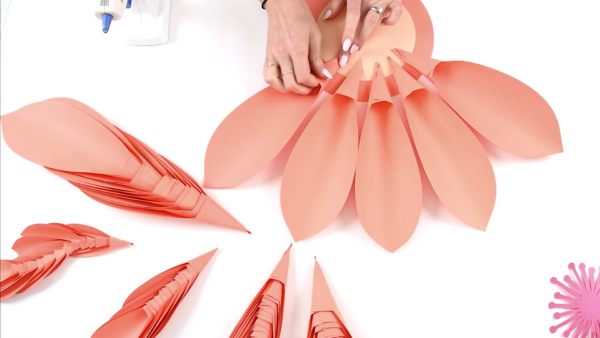 Attaching large rolled paper dahlia flower petals to the center of the paper flower. 
