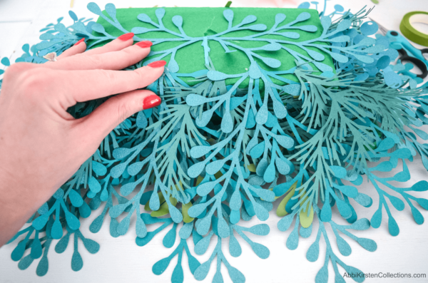 Abbi covers the foam blocks in springs of paper greenery, cut from a blue cardstock paper.