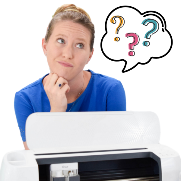 In a white room, Abbi Kirsten sits behind a Cricut cutting machine looking confused while cartoon question marks float in a thought bubble to her side. 