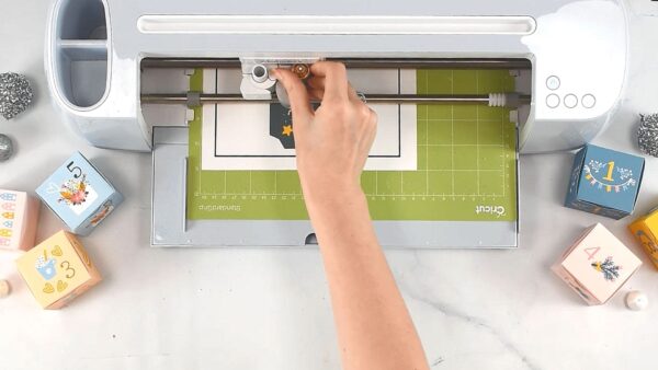 Abbi Kirsten's arm adjusts her Cricut machine to Print then Cut the advent calendar boxes. 