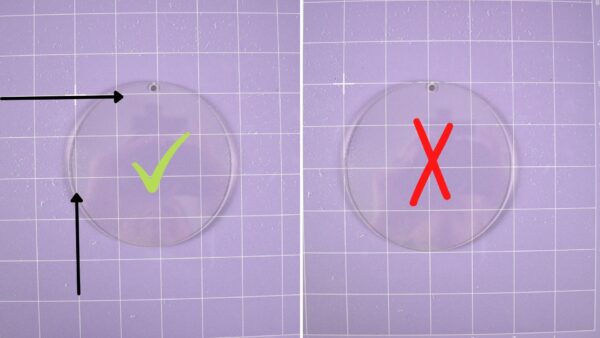 Two side-by-side images showing how to line an acrylic disk ornament up on a purple Cricut cutting mat. The image on the left is lined up correctly with a yellow checkmark in the center; the image on the right has a red x in the center, indicating it is not lined up correctly.