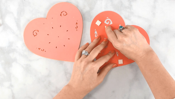 3D foam tape being applied to a peach-colored paper heart on a marble workstation. 