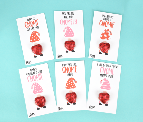 White, small, gnome valentine card printables on a sea-green backdrop. Each gnome holds a candy heart and has a pun Valentine phrase like "There is gnome one like you" and "You are my one and gnomely."