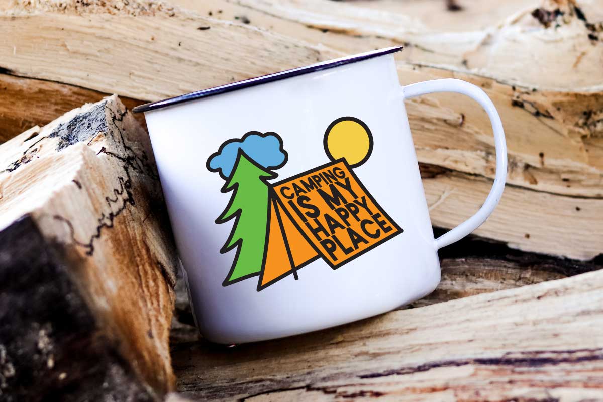 A white metal mug with a simple camping illustration on the front sits on firewood.