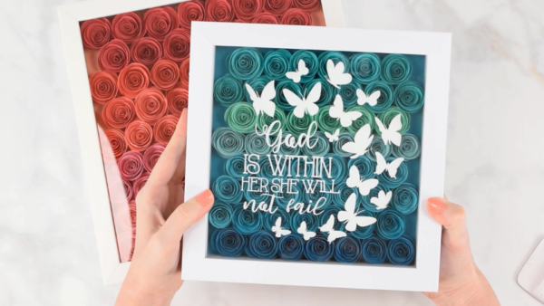 Create an easy DIY shadow box with rolled paper flowers and your Cricut. Learn the best way to apply vinyl to your shadow box and discover more cricut shadow box ideas!