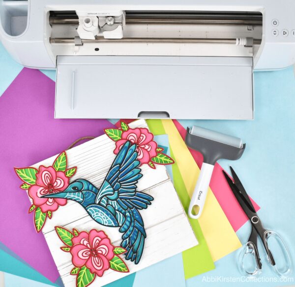 Paper hummingbird and flower craft with cardstock, Cricut machine, scissors and brayer tool. 