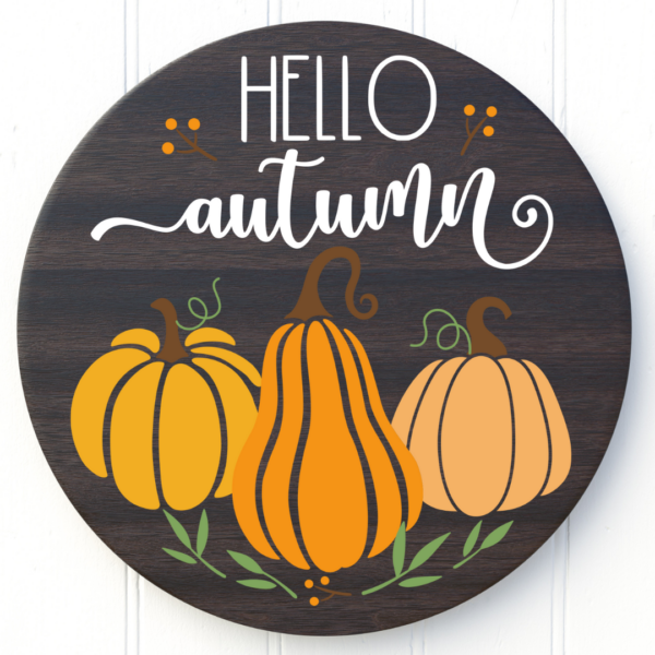 "Hello autumn" is above orange pumpkins on a brown wood circular sign. 