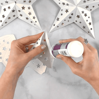 Overhead shot hands gluing together two ends of the paper star template