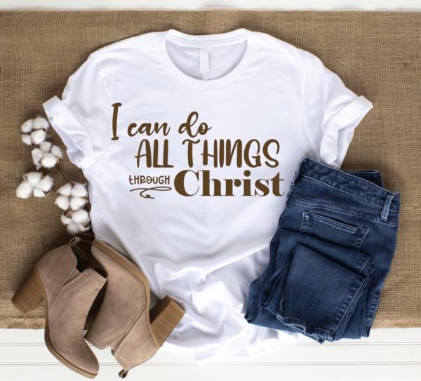 Jeans, brown shoes, and a white t-shirt that says "I can do all things through Christ" lay on a burlap background.
