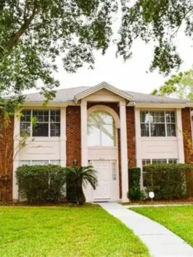A double storey house made with red brick and a manicured lawn, shot during daytime