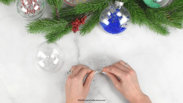 The images shows acetate being rolled to fit inside a clear plastic ornament. 