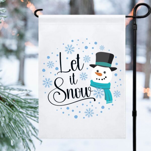 The image shows a garden flag with the phrase let it snow, a snowman and snowflakes. The design is a free SVG file on Abbi Kirsten Collections