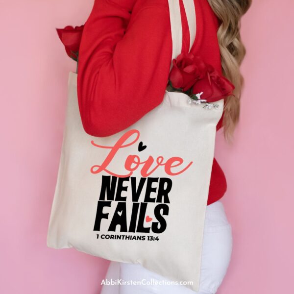 A woman facing sideways has a canvas bag on her shoulder that reads "love never fails 1 Corinthians 13:4." 