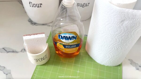The images shows how to clean your Cricut mat with dish soap, warm water and paper towels. 