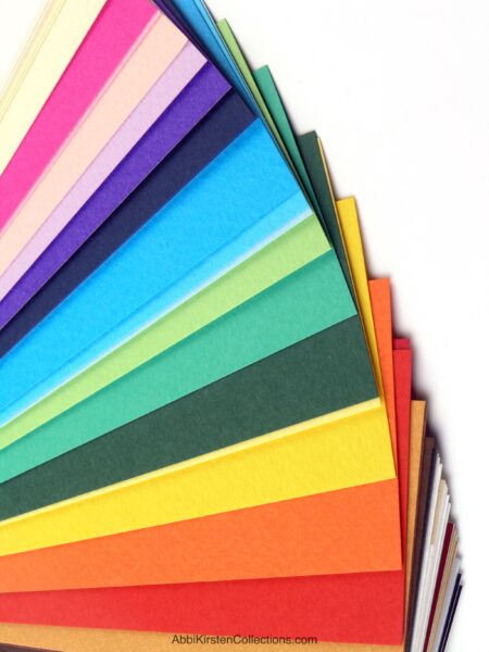 The images shows a pile of colorful cardstock to use with your Cricut machine. 