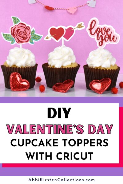 Three cupcakes with white frosting have three different cupcake toppers. One is a glittery rose, the other is two hearts with an arrow piercing them, and the third topper says, "Love you." The text below reads, "DIY Valentine's Day Cupcake Toppers with Cricut. "AbbiKirstenCollections.com" is in small print below the graphic. 