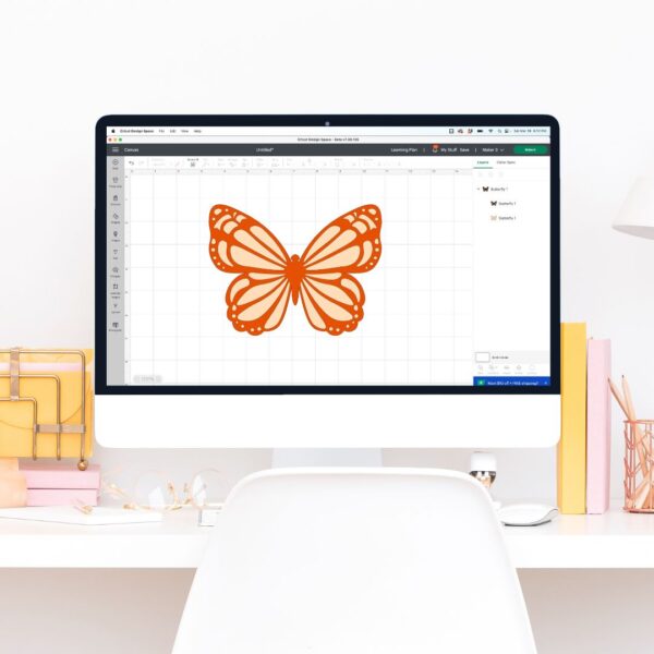 Mac computer on white desk with Cricut Design Space open and a butterfly image.