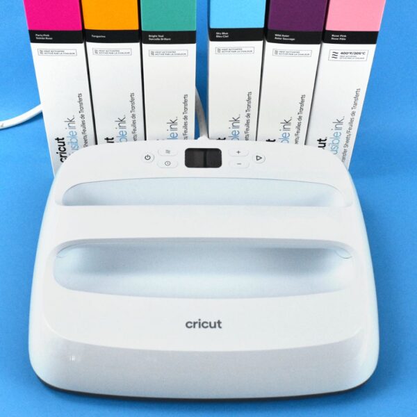 Six tall boxes of Cricut Smart Vinyl in various colors stand behind the Cricut Easy Press. The Easy Press is a great tool for heat transfer vinyl crafts.