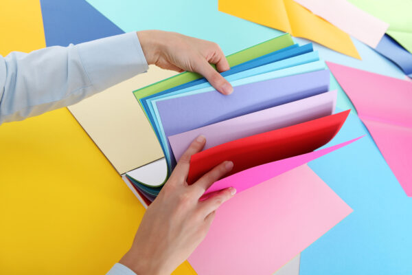 Abbi Kirsten's hands choosing color paper from a stack of scrapbook paper.