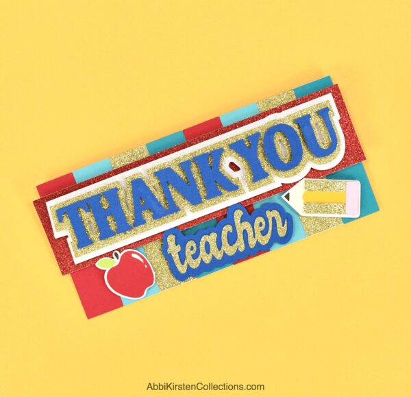 The image shows a 3D greeting card that reads "thank you teacher." The appreciation card, which has an apple and a pencil on it, was made with Cricut. 