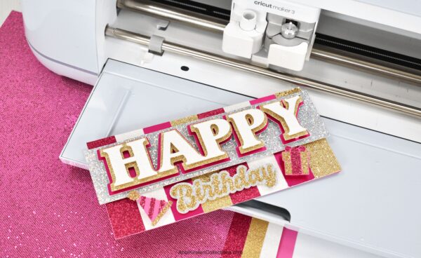 The image shows a pink and gold happy birthday card made with a Cricut machine. Learn how to make cards with Cricut. 