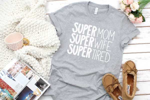 The image shows a grey tshirt with white iron on vinyl that says, Super Mom, Super Wife, Super Tired