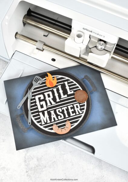 The image shows a handmade father's day card that says, Grill Master with a grill and meat made from cardstock. 