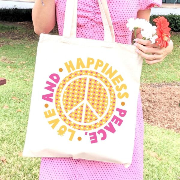 The image shows a tote bag with a iron-on vinyl design using patterned vinyl. The design says, peace love and happiness.