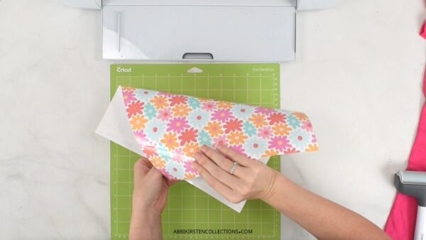 The image shows a floral pattern heat transfer vinyl being placed onto a Cricut cutting machine mat.