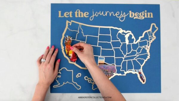 This image shows a USA map in gold vinyl with a blue matboard. A crafter is filling the map with personal travel photos. 