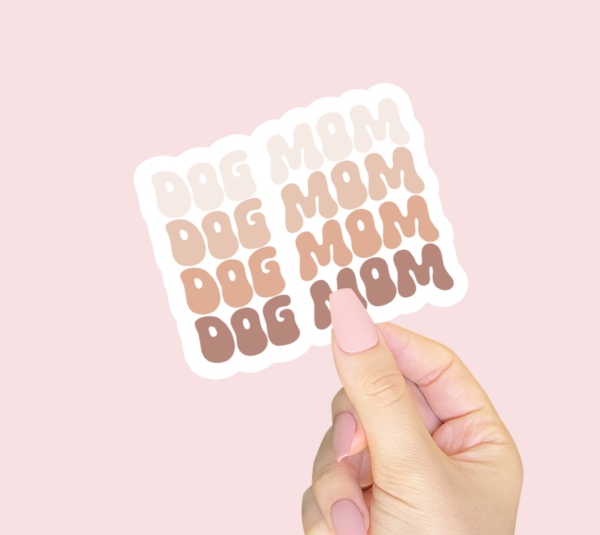 A hand holding a dog Mom sticker 