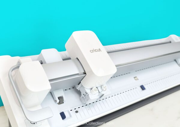 Cricut Venture machine on a white desk with a blue wall background