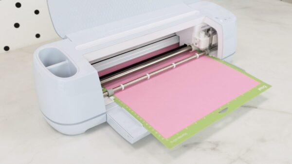 Pink cardstock paper being cut on a Cricut maker machine