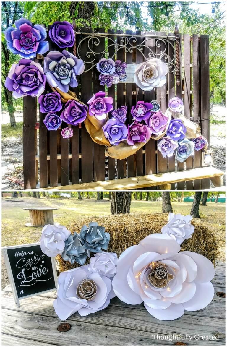 A collage of two paper flower backdrops. The top photo features paper flowers in various shades of blue and purple hanging on a wooden fence. The bottom photo features white flowers, all giant and arranged around hay bales. The largest flower has white fairy lights wrapped around it.