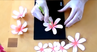 Abbi Kirsten uses a shaping tool to create a concave indent in the center of the petal layer. This action makes the paper petals curl to the center, creating a more realistic bloom.