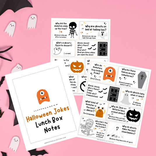 Fun Halloween printable lunch box notes lay on a pink surface with paper ghosts and bats on the left border. One piece of paper reads, "Halloween Jokes Lunch Box Notes." The printable notes feature Halloween illustrations and fun, kid-friendly jokes. These cute free printables can be found on abbikirstencollections.com.