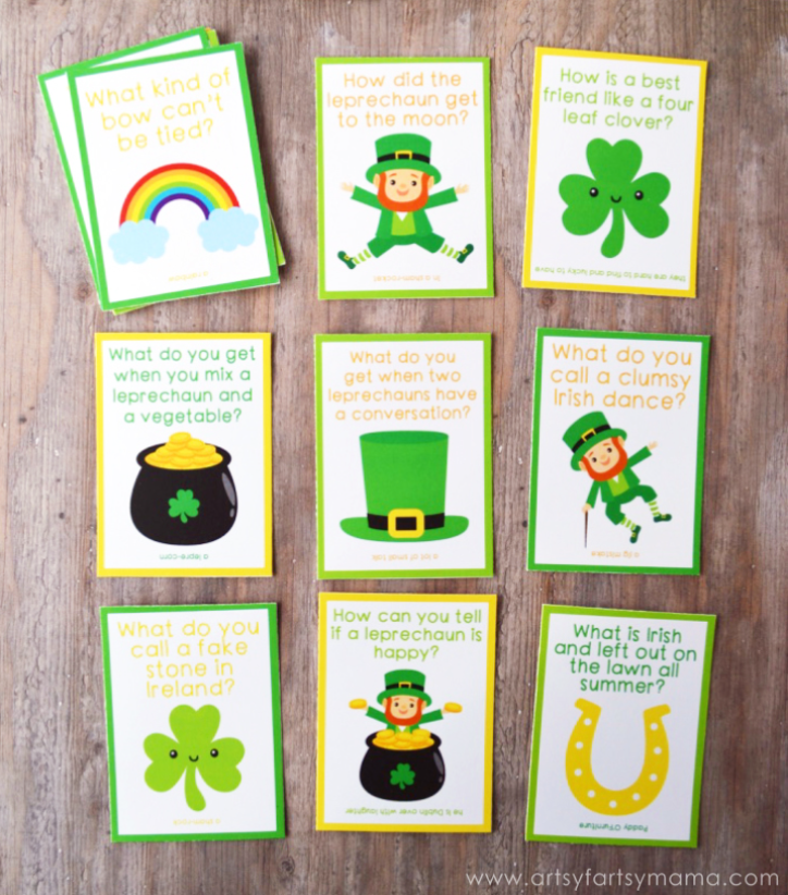 St. Patrick’s Day lunch box notes are arranged on a wooden surface. Each card features an illustration and a St. Patrick’s Day joke to brighten your student’s day. The free printable lunch box notes can be found on artsyfartsymama.com.
