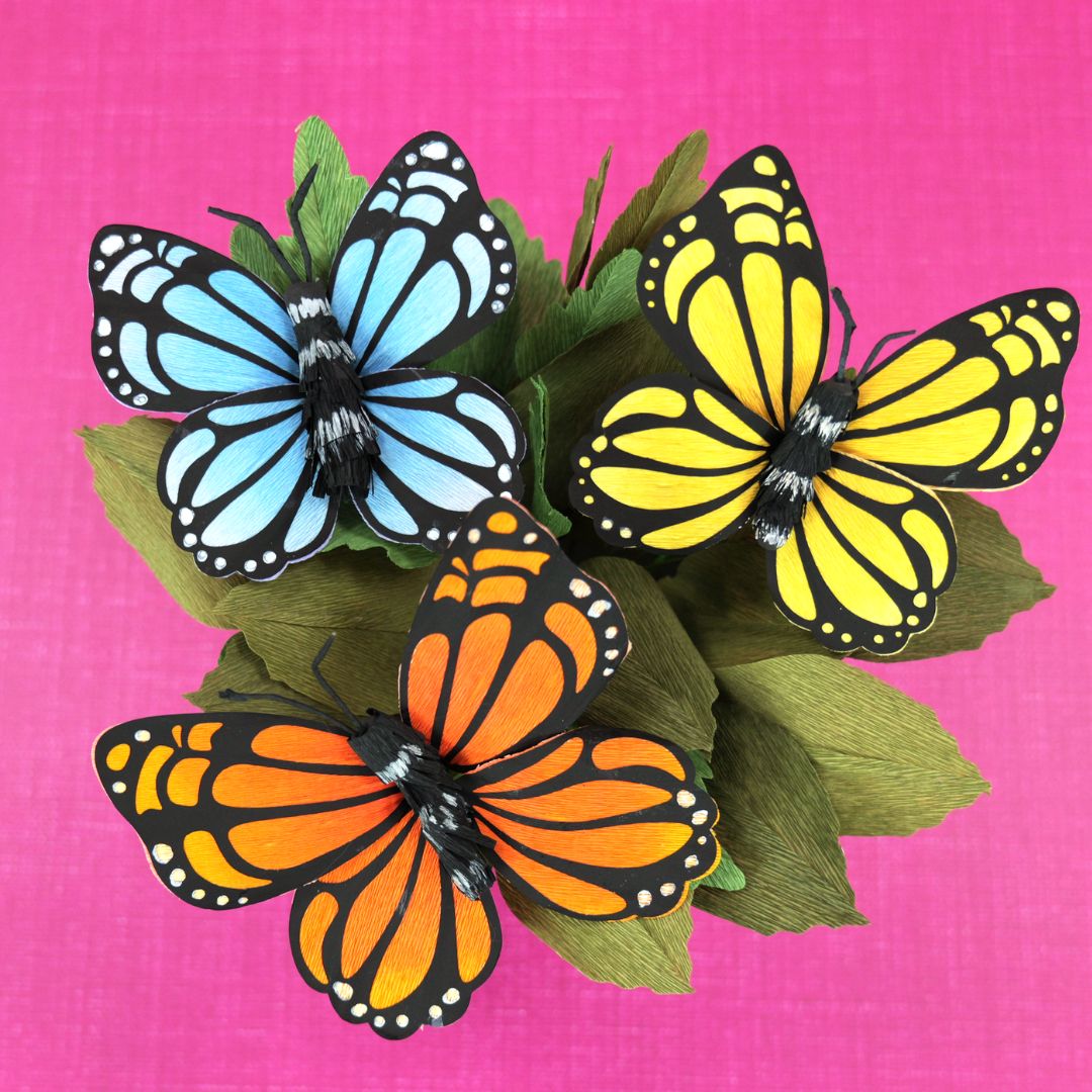 Crepe paper monarch butterflies in orange, blue and yellow.