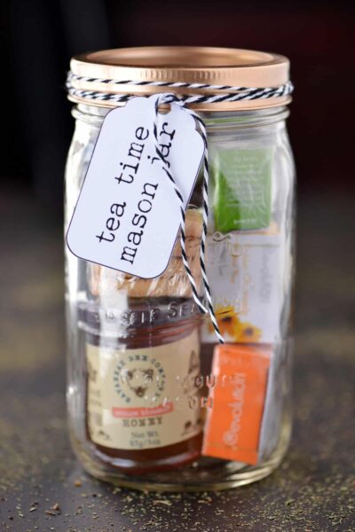 Mason jar filled with tea bags and honey, gold lid and label with text tea time mason jar