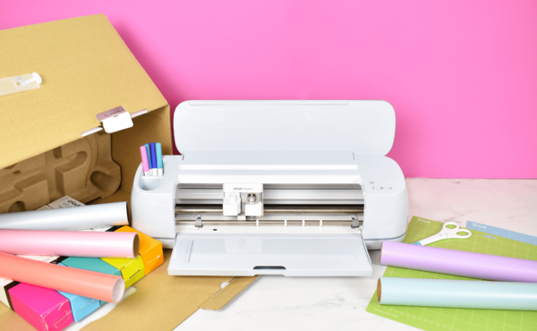 Cricut Maker on a desk with the box open and craft vinyl