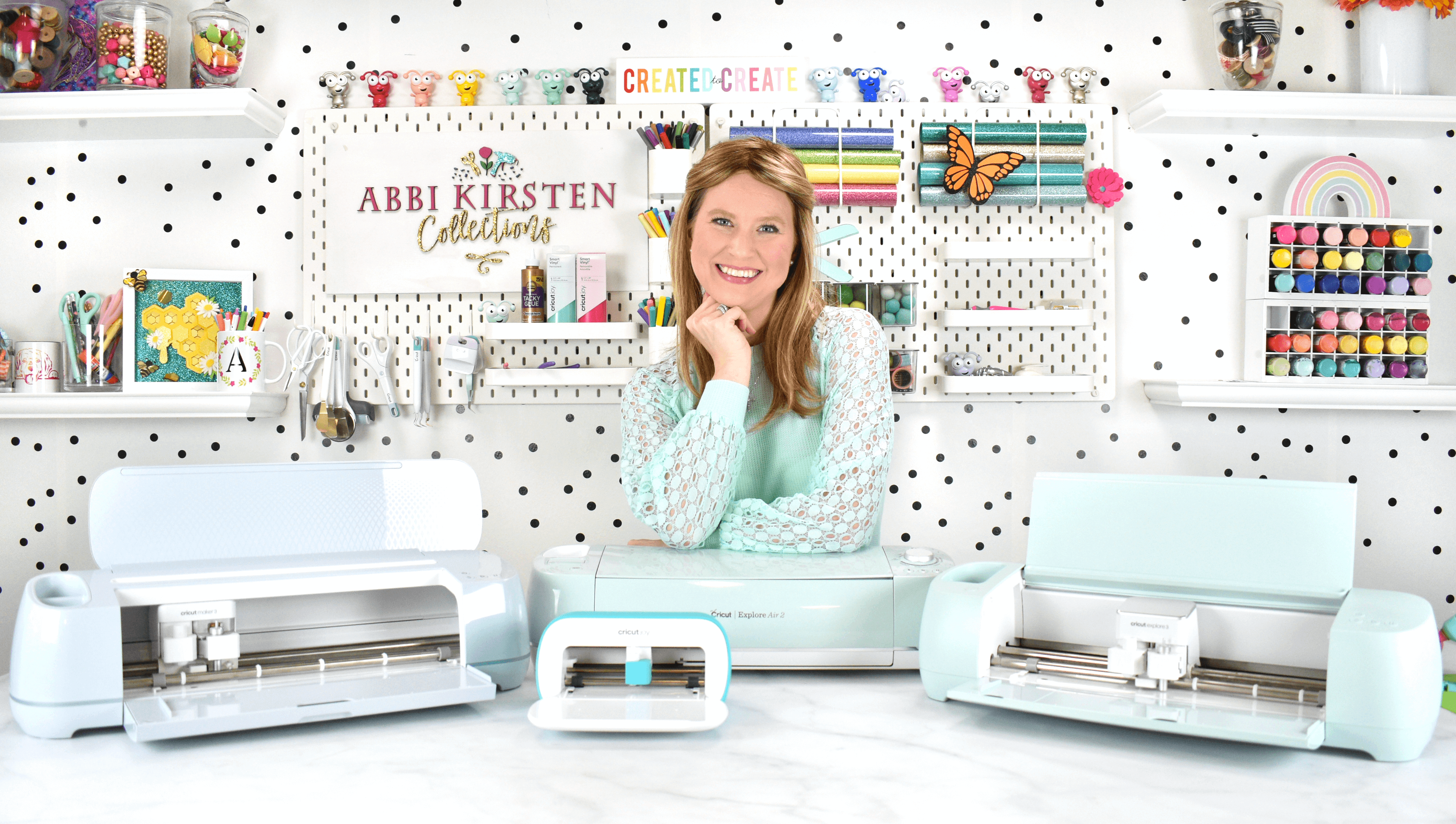 Abbi Kirsten smiling in from of several Cricut machines.